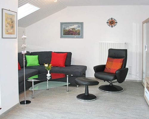 SPO-Hanack - Blick auf das gut beleuchtete Wohnzimmer mit Couch und Drehstuhl